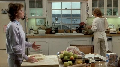 a woman standing in a kitchen next to a table filled with food