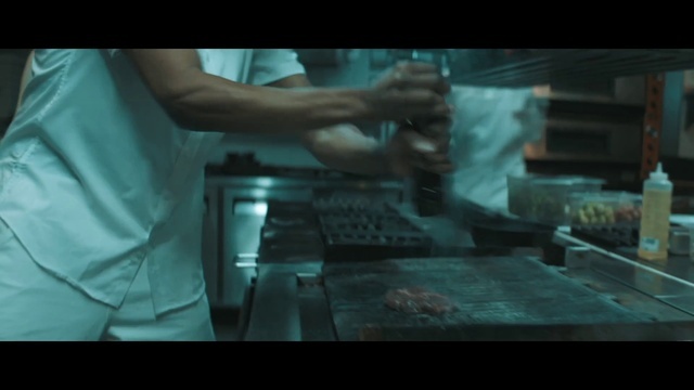 a person in a kitchen preparing food on a grill