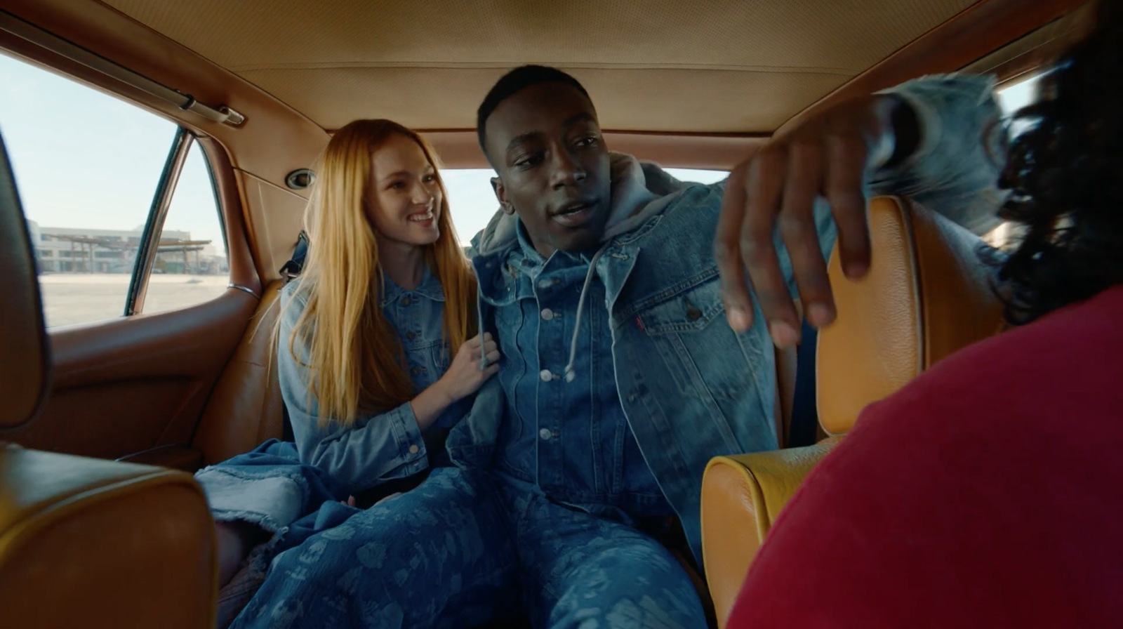 a man and a woman sitting in the back of a car