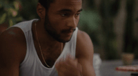 a man wearing a white tank top sitting down