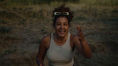 a woman in a tank top is smiling and waving