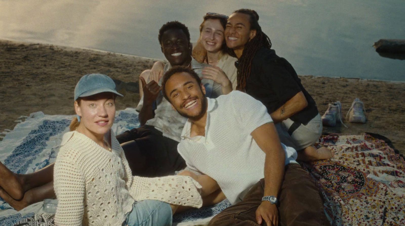 a group of people sitting on a blanket on the beach