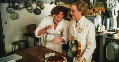 a couple of women standing next to each other in a kitchen