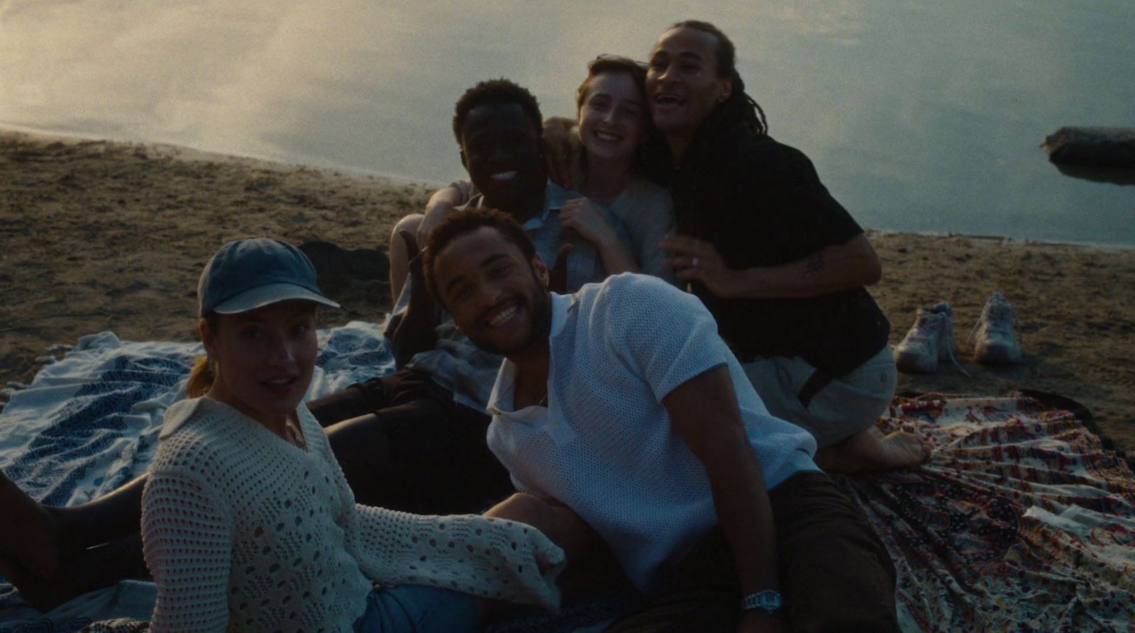 a group of people sitting on top of a blanket on a beach