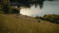 a person standing on a hill next to a body of water