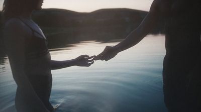 a man and a woman holding hands over a body of water