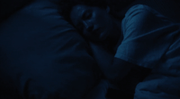 a man sleeping in a dark room with his head on a pillow