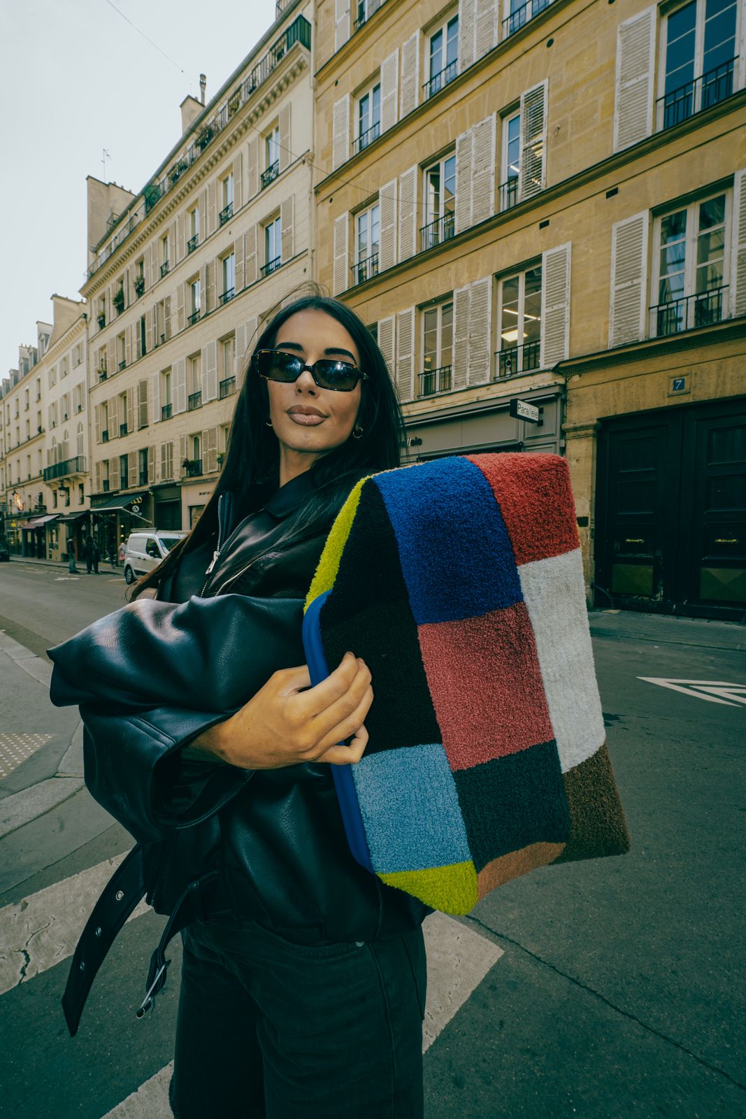 a woman holding a multicolored blanket on a city street