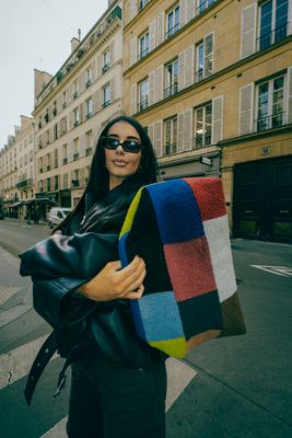a woman holding a multicolored blanket on a city street