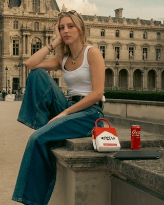 a woman sitting on a ledge in front of a building