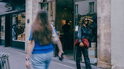 two women walking down the street in front of a store