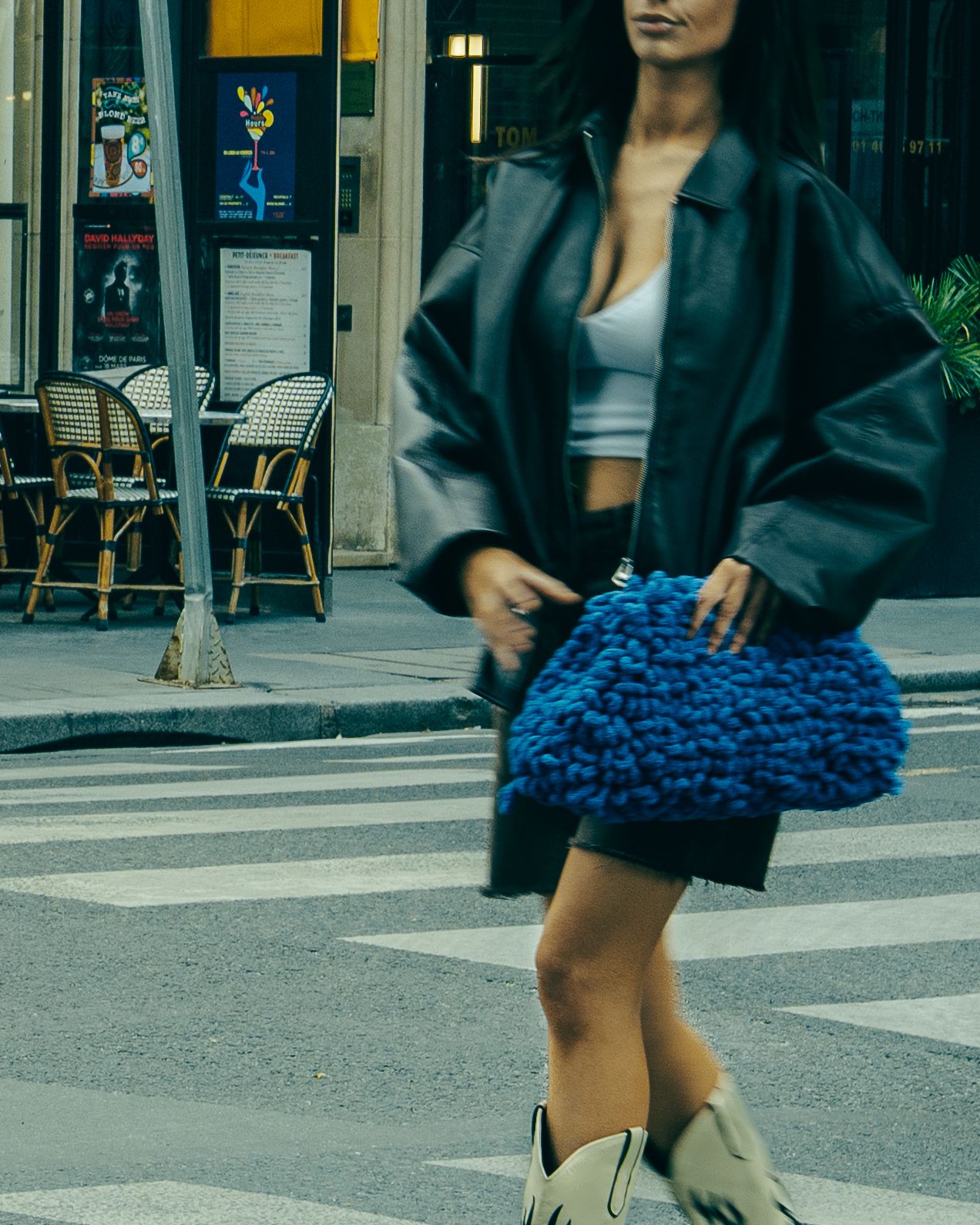 a woman walking across a street holding a purse