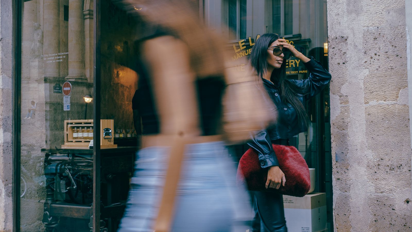 a woman walking down a street next to a tall building