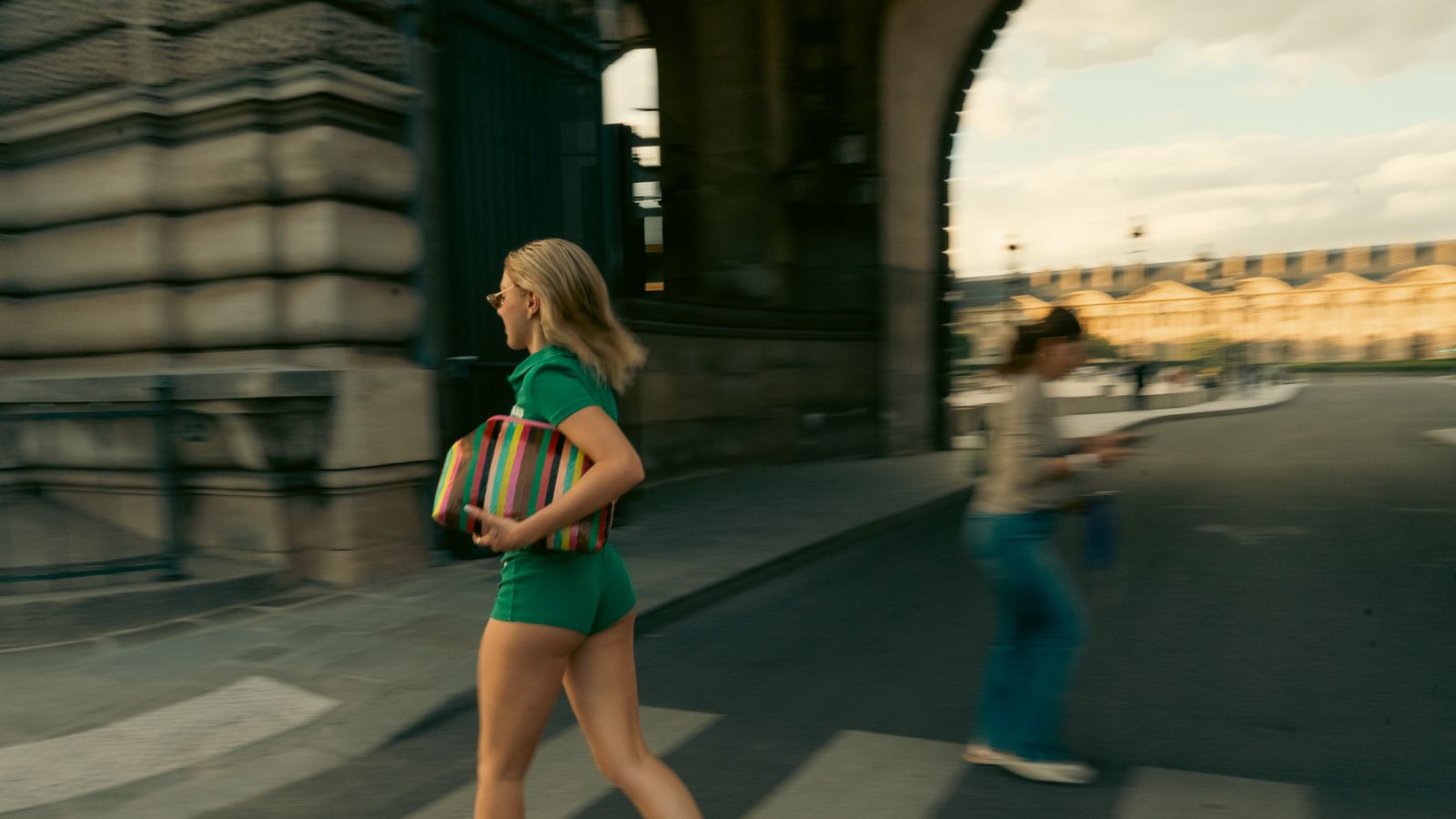 a woman in a short green dress is crossing the street