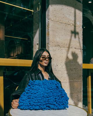 a woman sitting at a table with a blue blanket on it