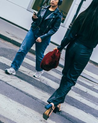 a woman walking across a street holding a red purse