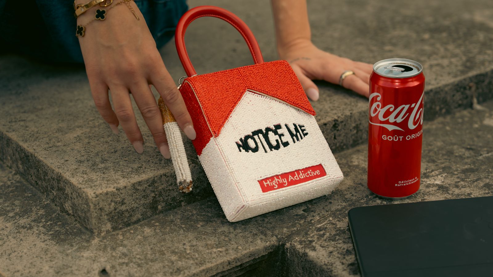 a handbag with a house on it next to a coca - cola can