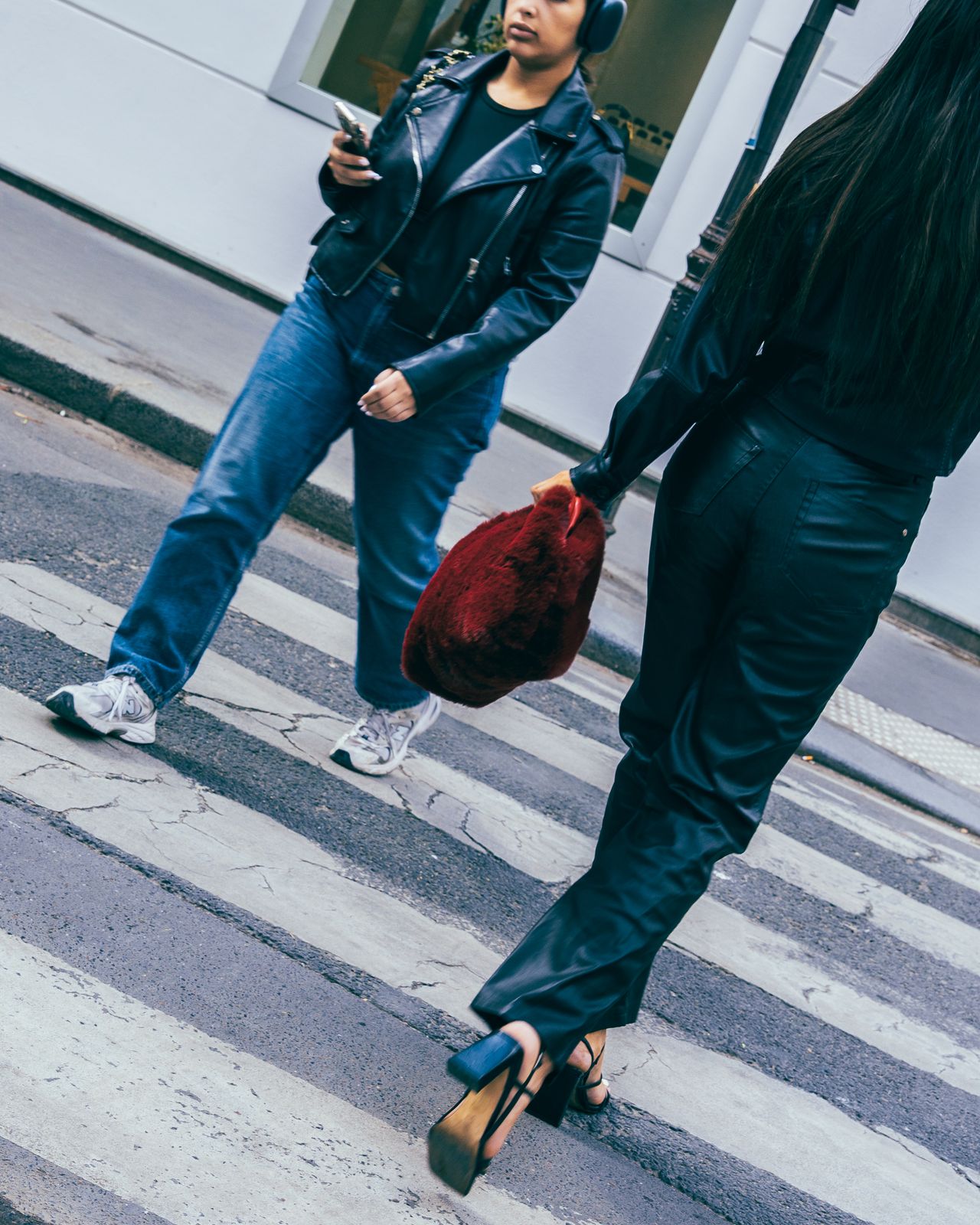 a woman walking across a street holding a red purse