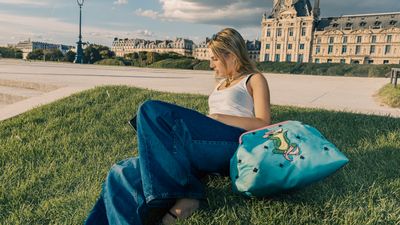 a woman sitting on the grass with a handbag