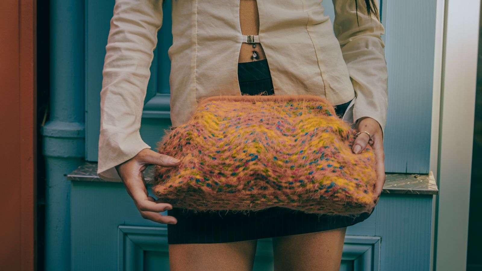 a woman is holding a purse made of yarn