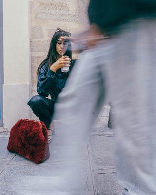 a woman sitting on the ground with a cell phone