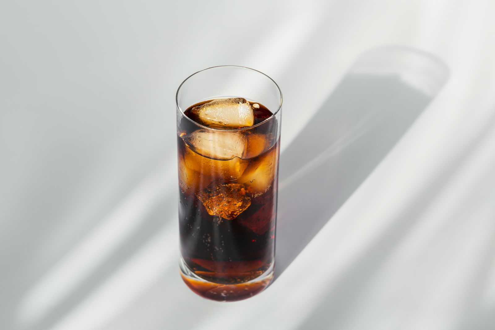 a glass of soda with ice cubes in it