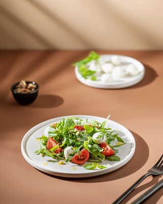 a white plate topped with a salad next to a fork