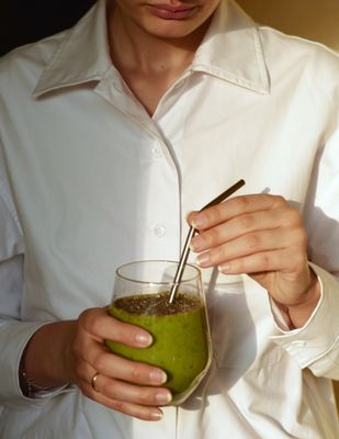 a woman holding a glass of green smoothie