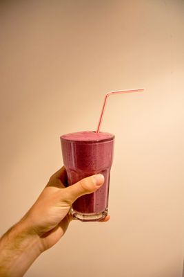 a hand holding a glass with a straw in it