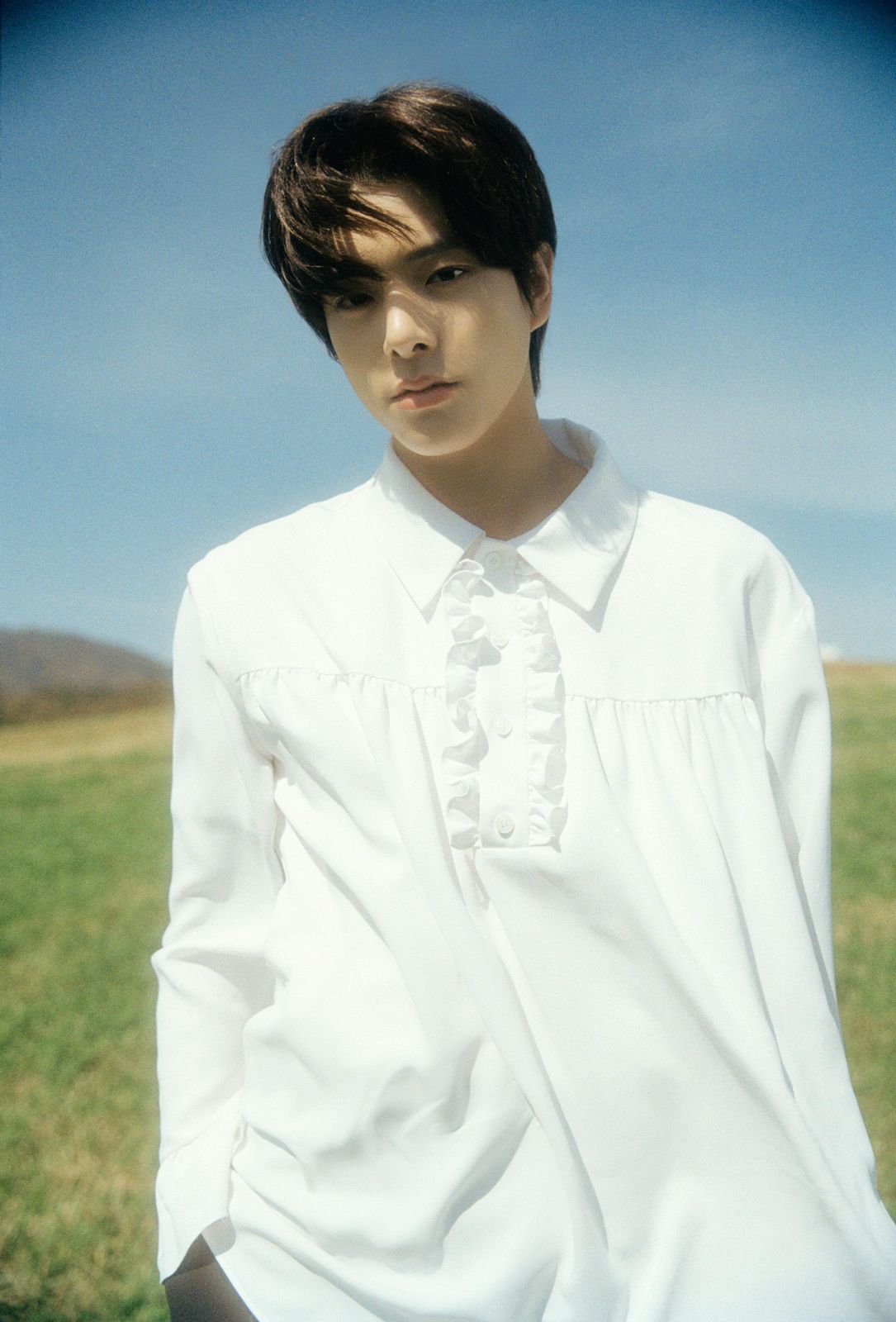 a man in a white shirt and tie standing in a field