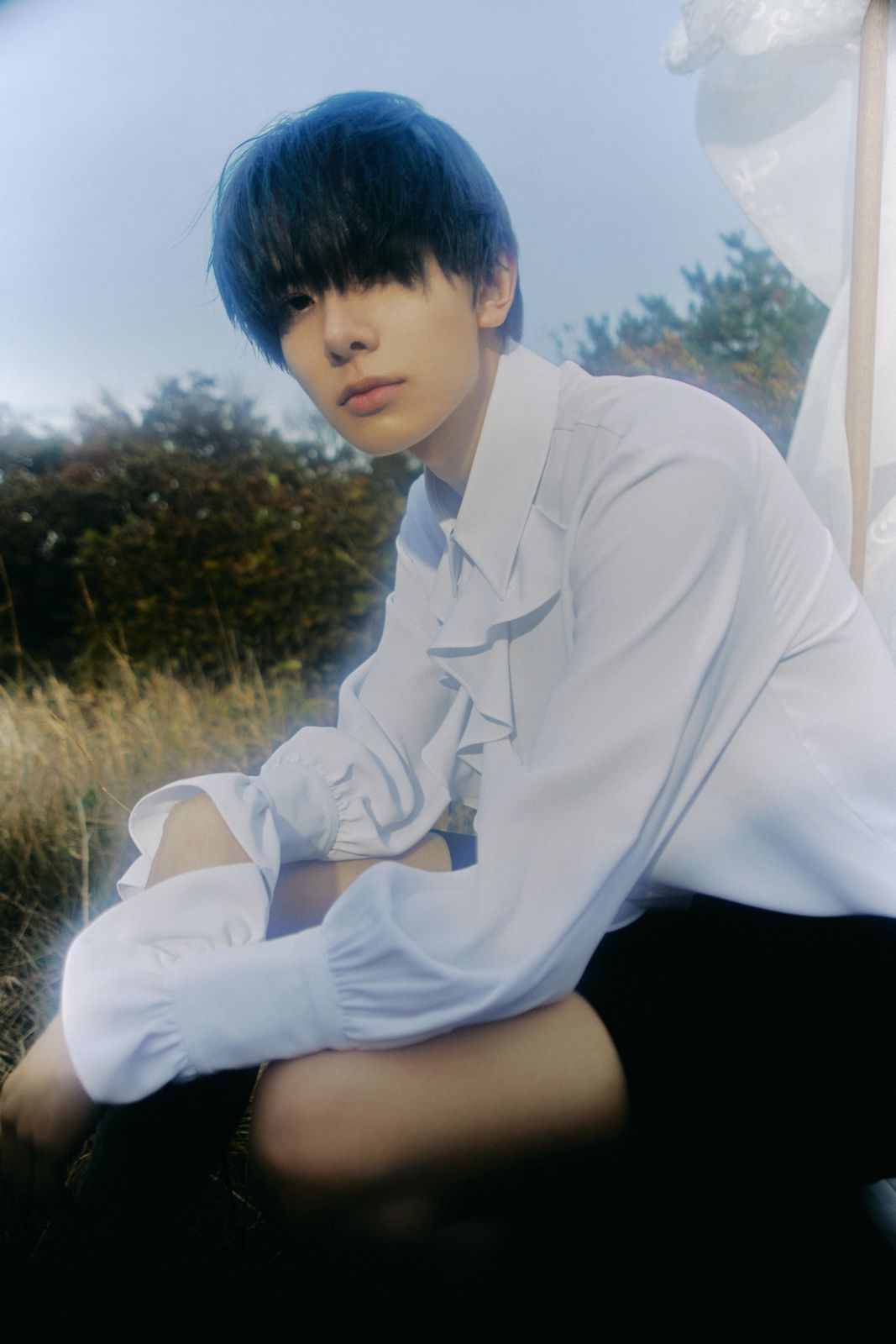 a man sitting on the ground in a white shirt