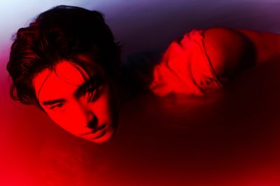 a young man laying down in a red light