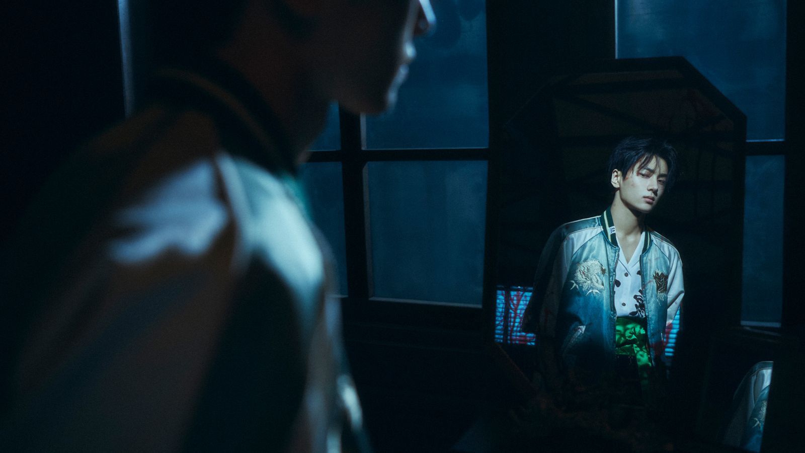 a man standing next to a window in a dark room