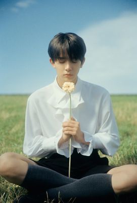 a man sitting in a field holding a flower