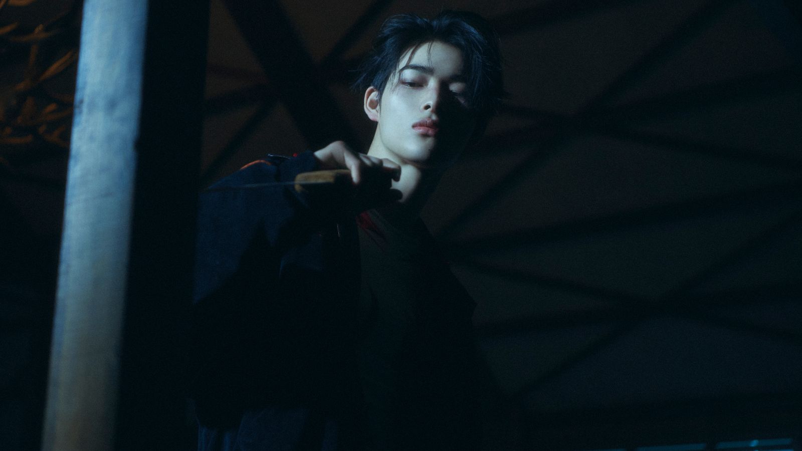 a young man holding a baseball bat in the dark