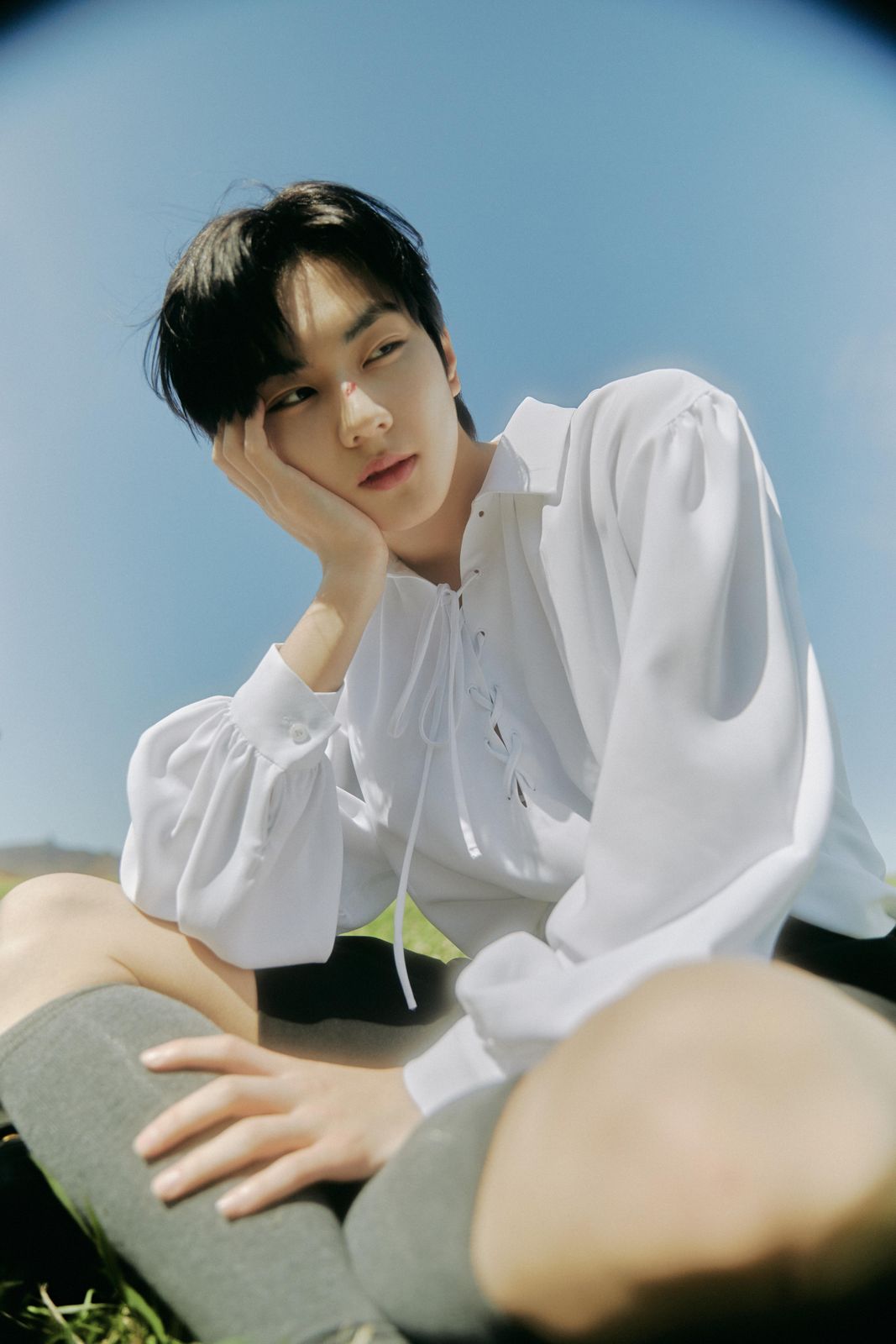 a man sitting on the ground wearing a white shirt