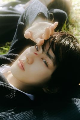 a young man laying on the grass with his hands on his head