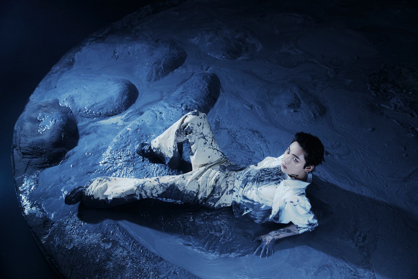 a man laying on the ground next to a rock