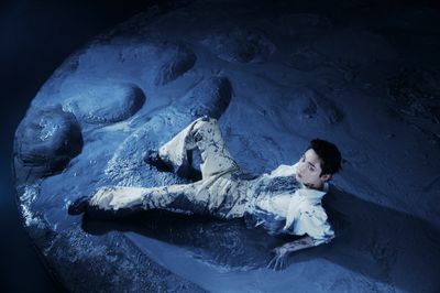 a man laying on the ground next to a rock