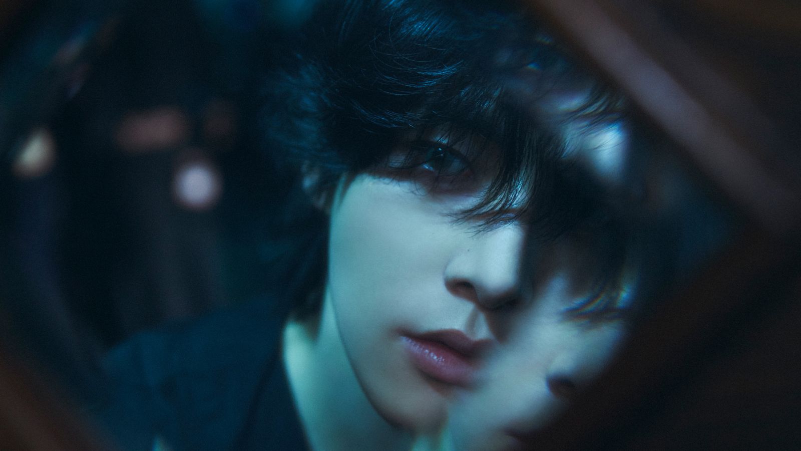 a man with black hair looking at himself in a mirror