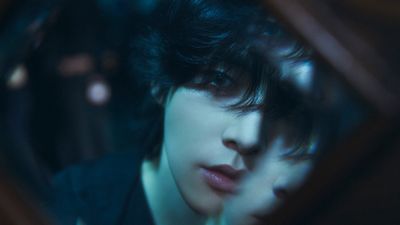 a man with black hair looking at himself in a mirror
