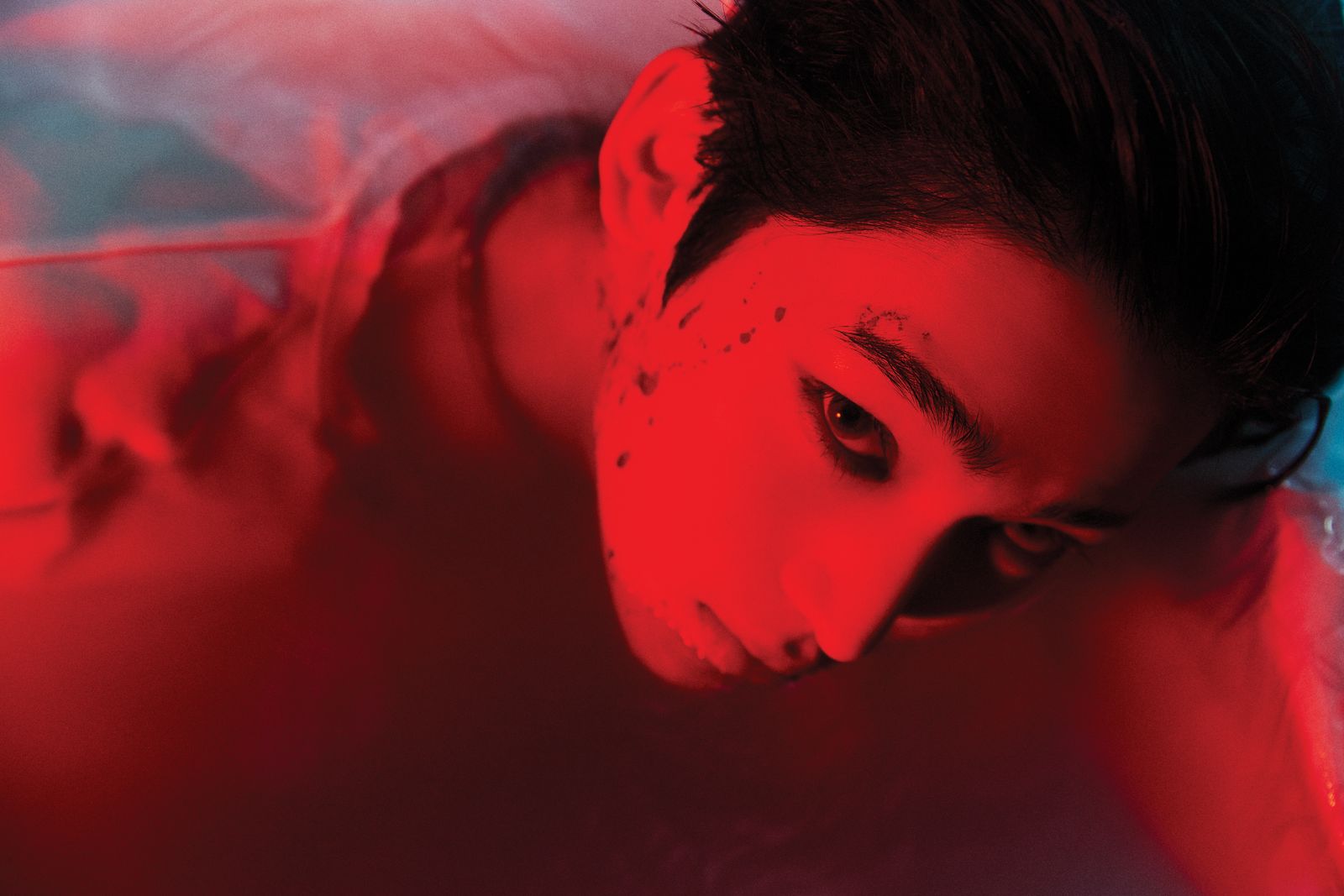 a woman in a bathtub with a red light on her face