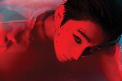 a woman in a bathtub with a red light on her face