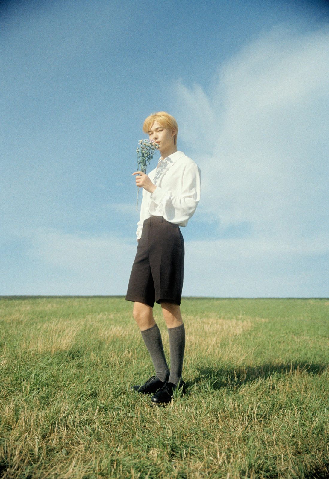 a man standing in a field holding a flower