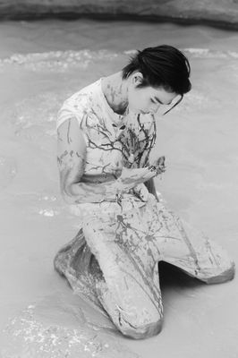 a man sitting on a rock in the water