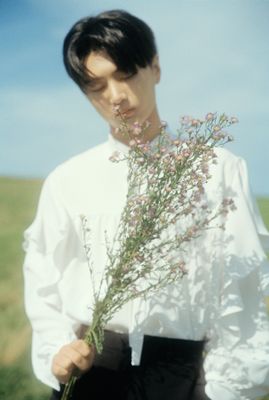 a man in a white shirt holding a bunch of flowers