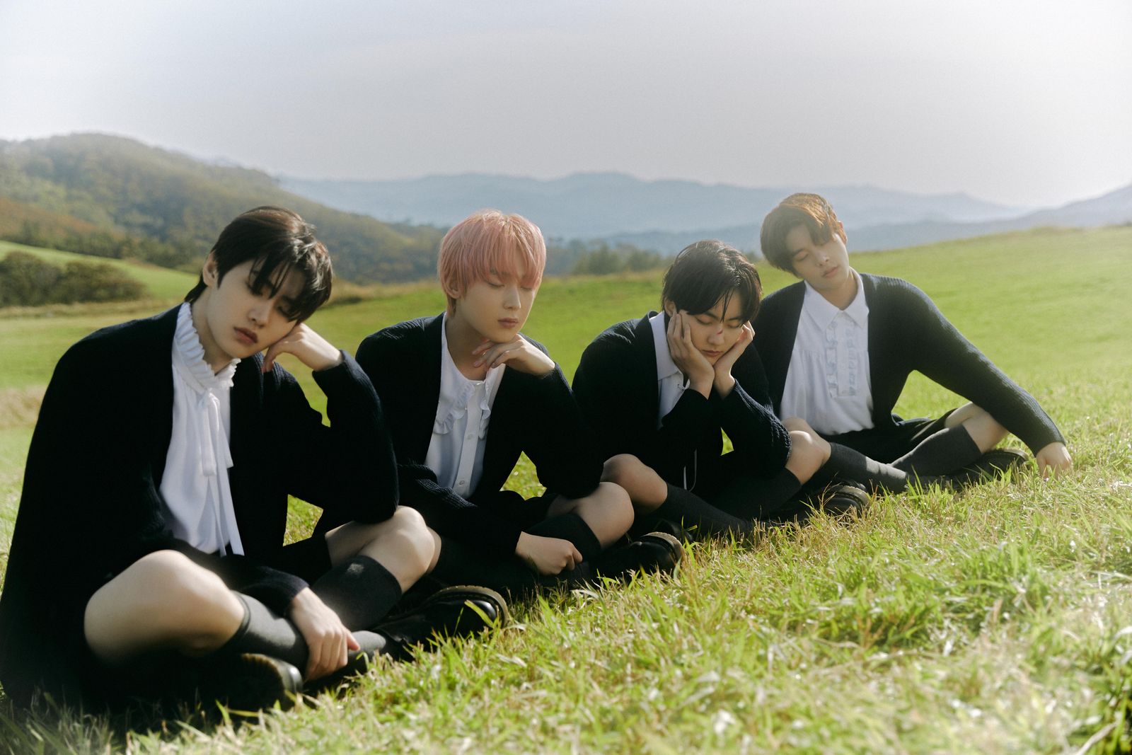 a group of young men sitting on top of a lush green field