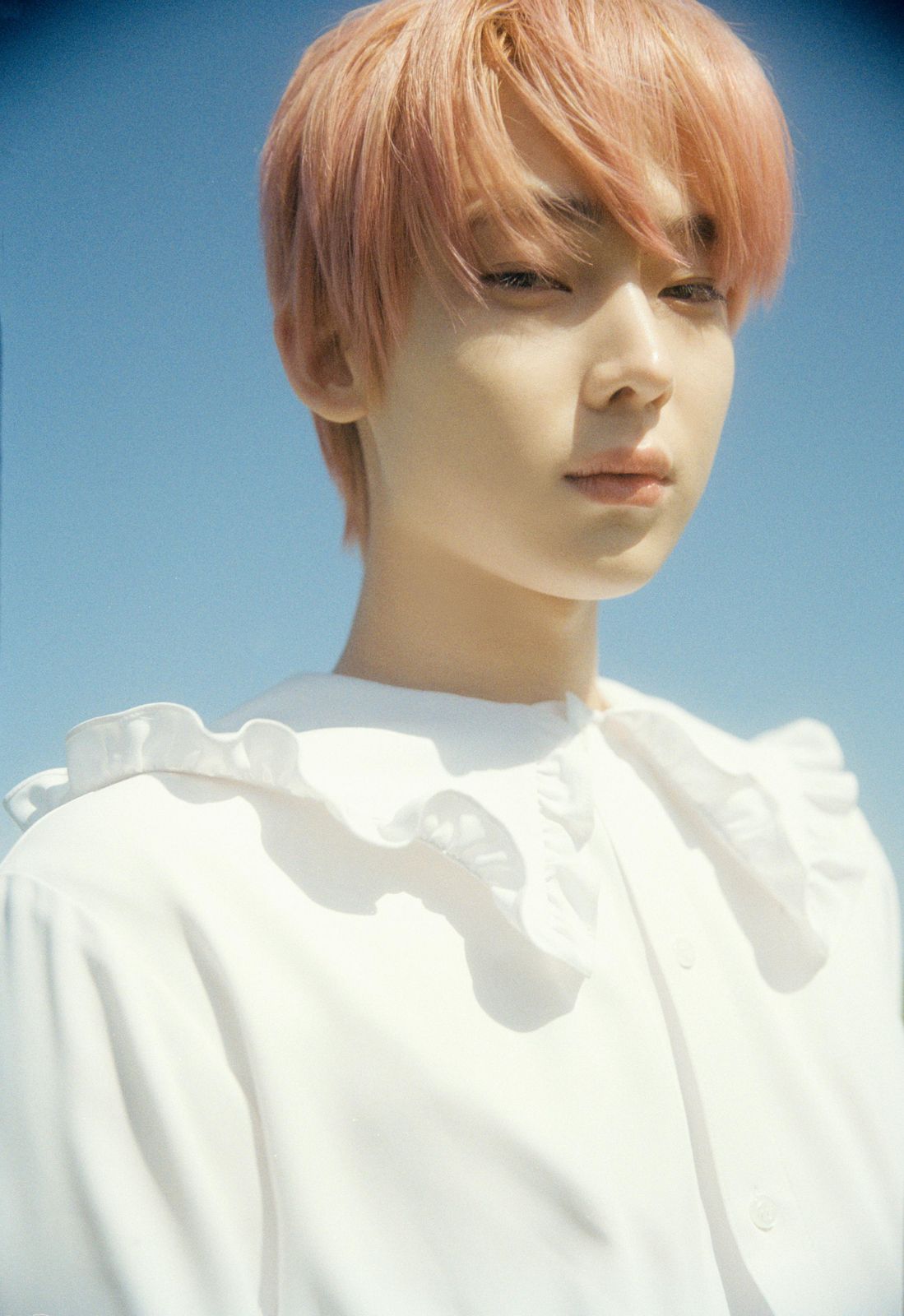 a man with pink hair wearing a white shirt