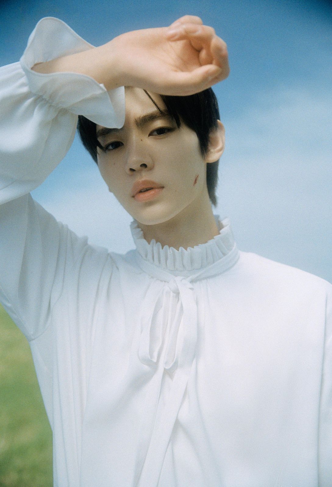 a woman in a white shirt holding her hand up to her head