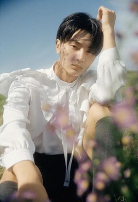 a young man sitting in a field of flowers